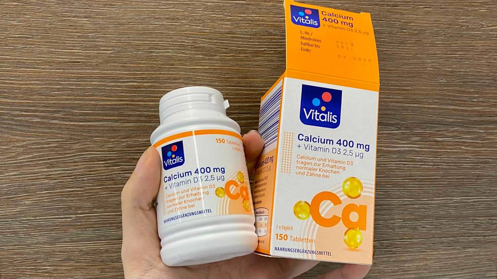 Im Test: Hand hält eine Dose und eine offene Verpackung mit Vitalis Calcium.