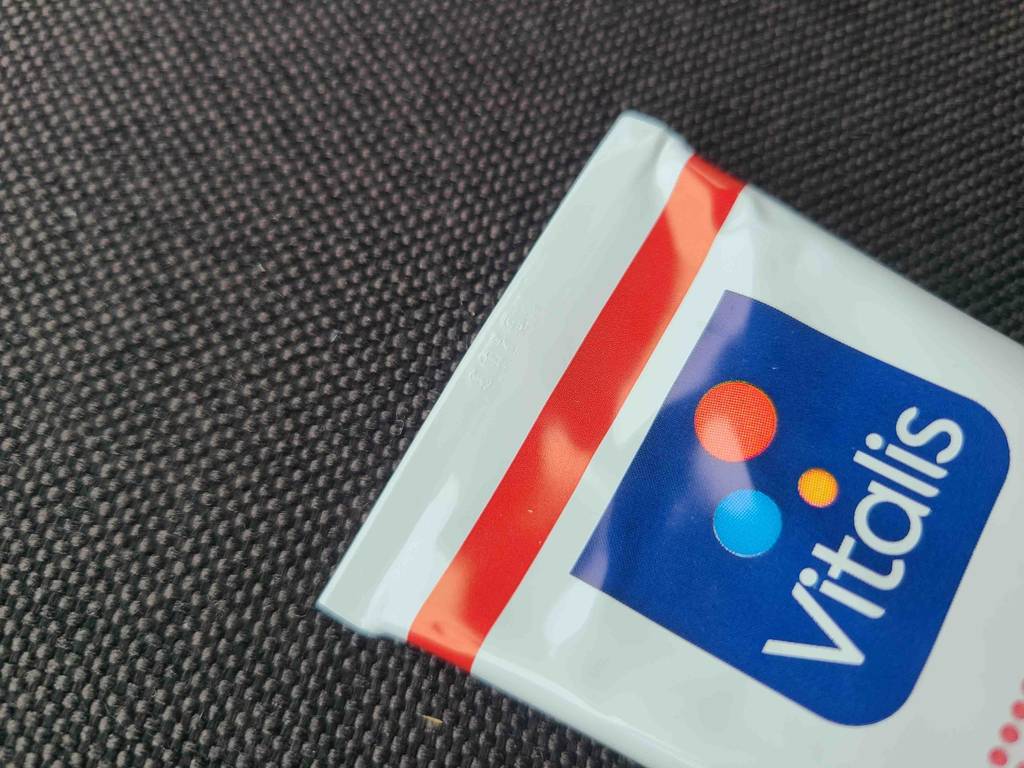 Das ende einer weißen Tube von VITALIS mit der getesteten Wärmesalbe liegt auf einer schwarzen Oberfläche.