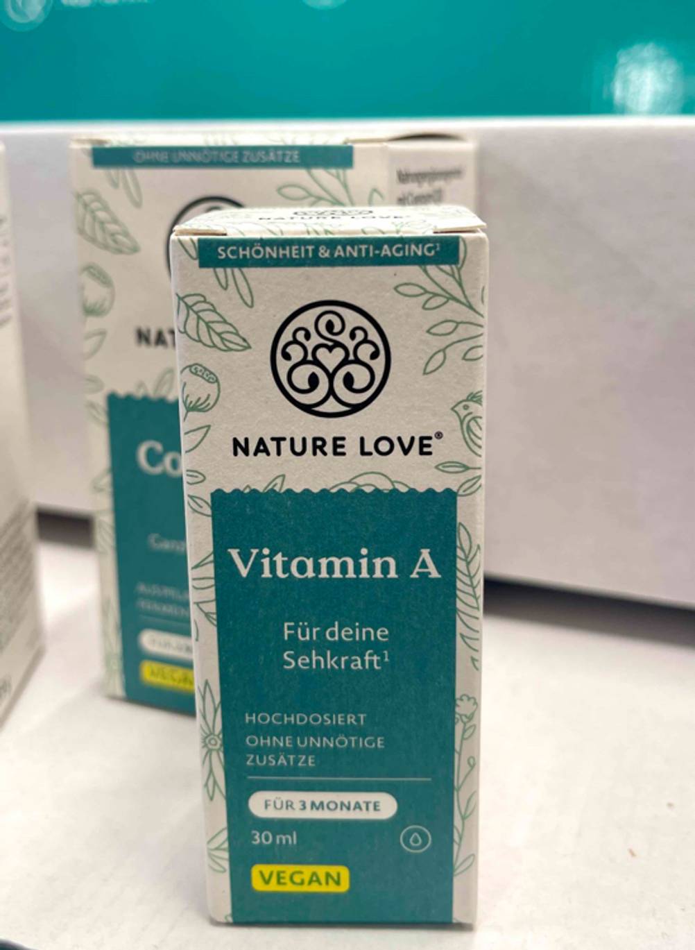Mehrere Packungen Vitamin A stehen zum testen versetzt hintereinander auf einem weißen Regal.