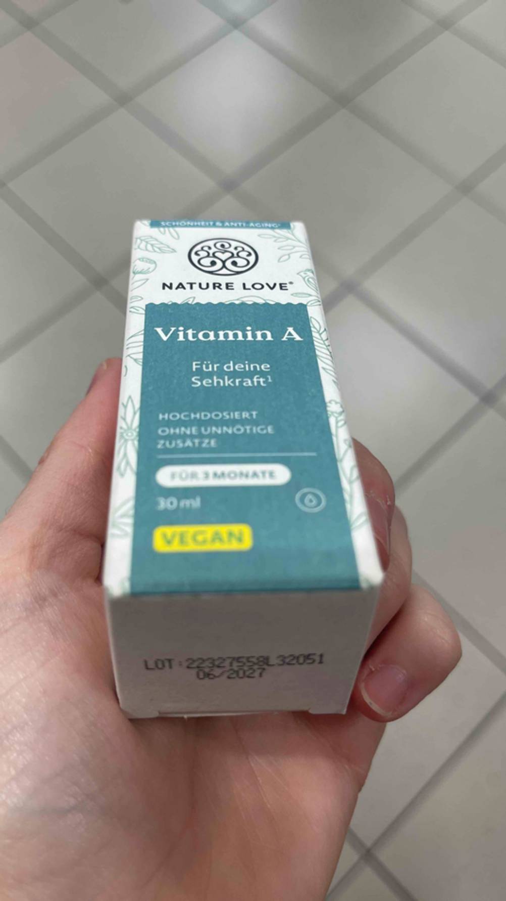 Eine Hand hält eine Packung getestetes Vitamin A mit der Unterseite nach vorn.