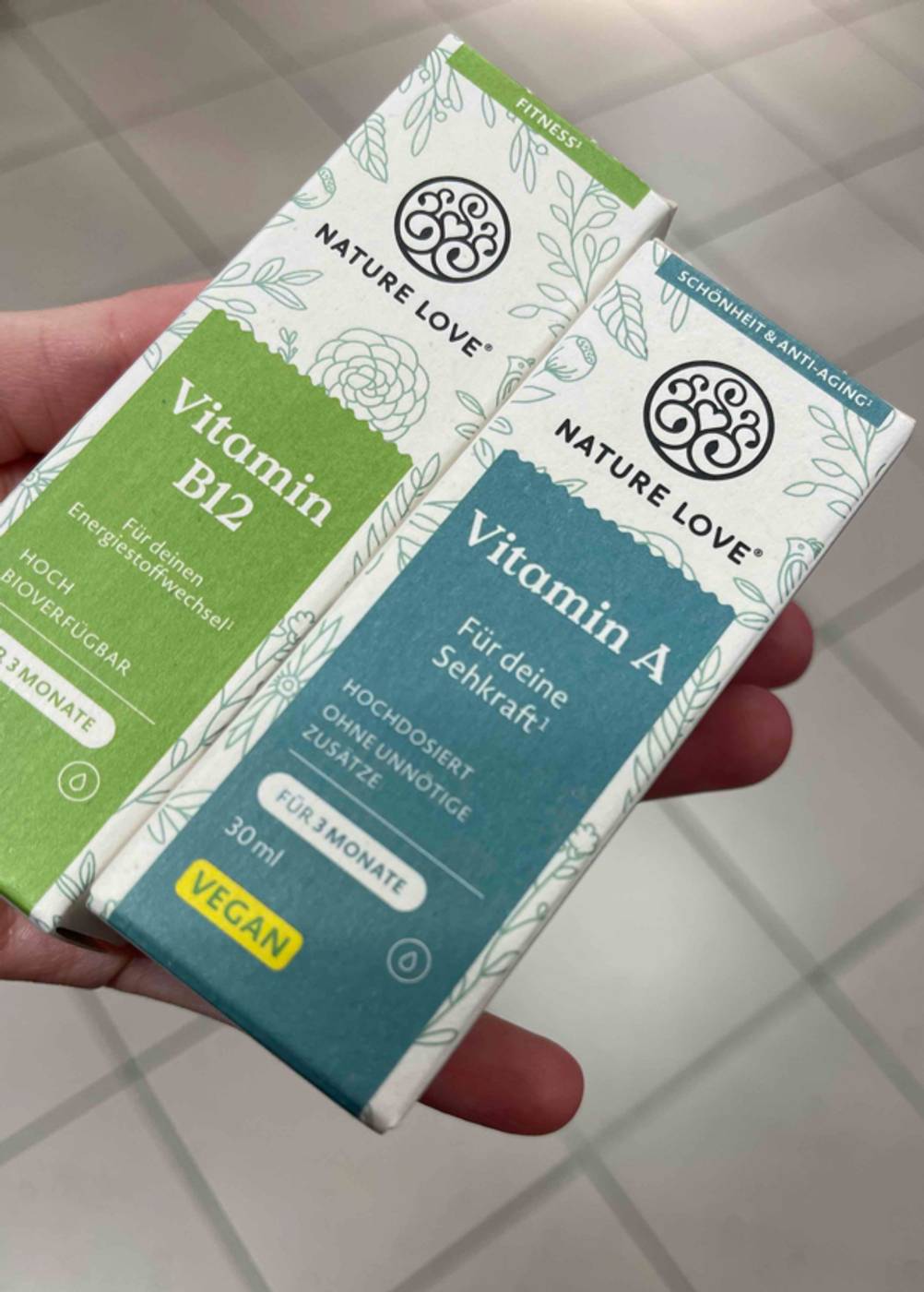 Vitamin A im Test: Eine Hand hält zwei Packungen unterschiedlicher Vitamine.