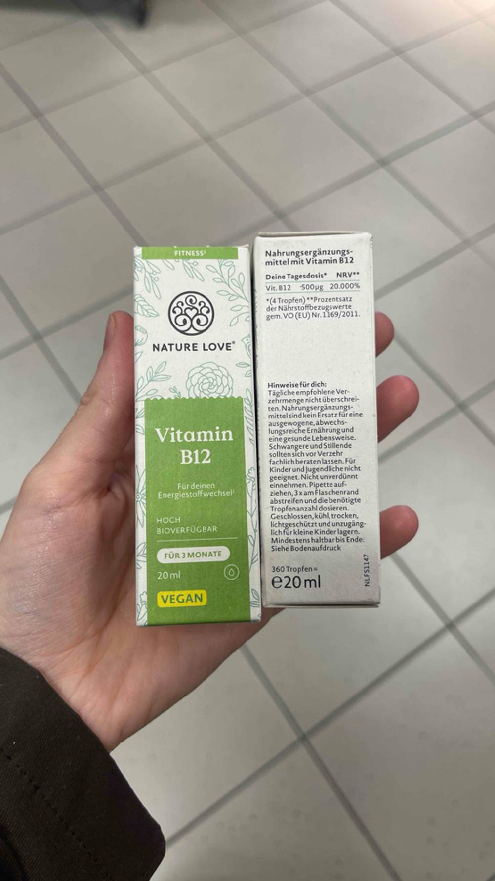 Zwei Packungen der getesteten Vitamin-B12-Tropfen gehalten von einer Hand.