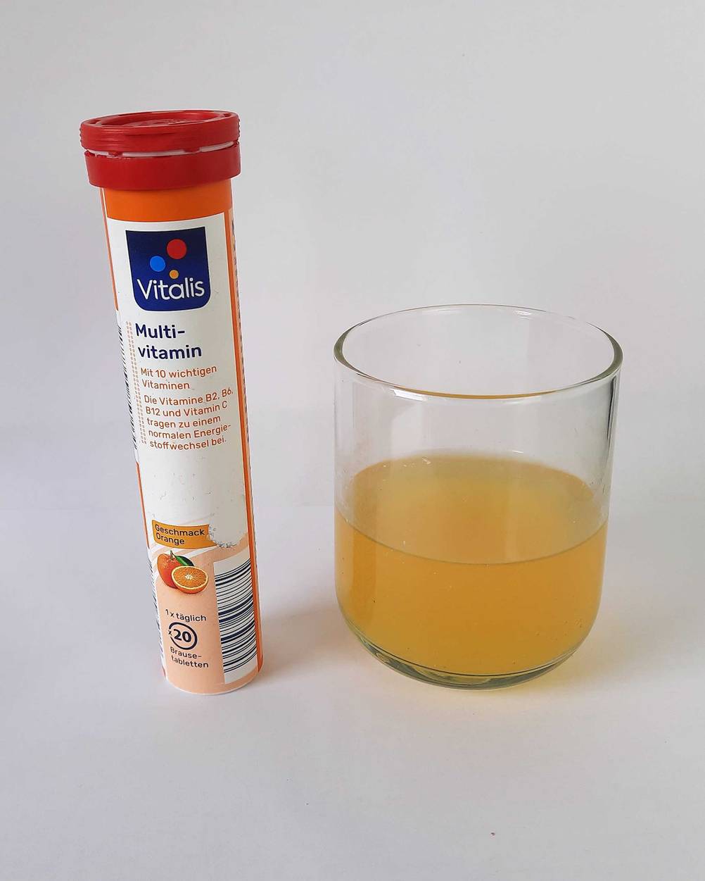 Neben einem Glas steht eine Dose der Vitamin-Brausetabletten im Test.