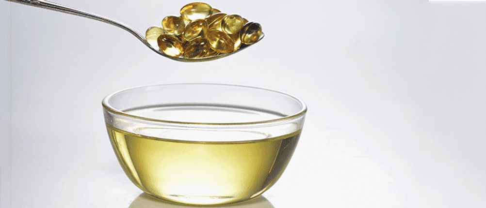 schale öl und darüber auf einem löffel vitamin d tabletten