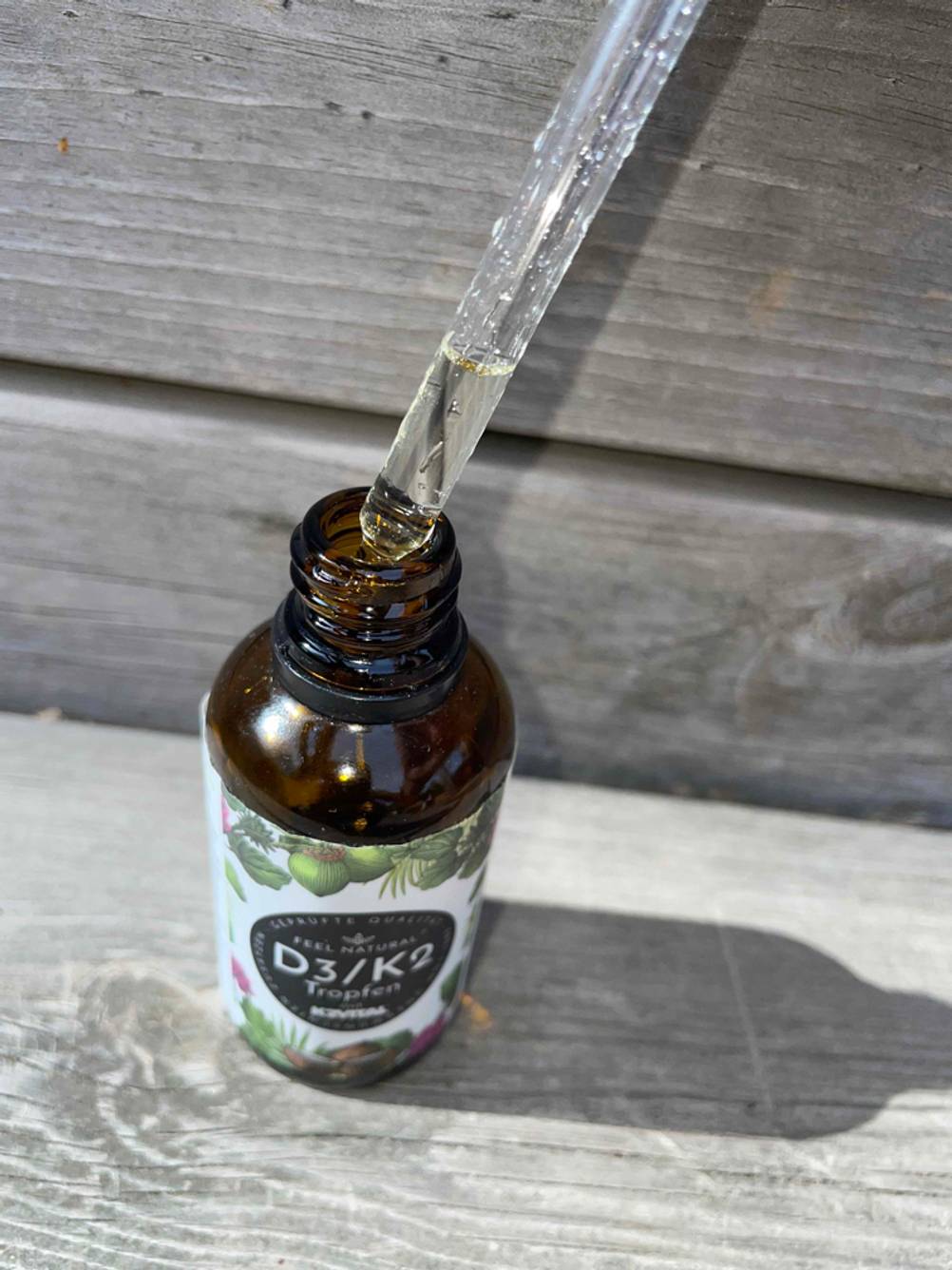 Vitamin-D3-K2 getestet: Eine Flasche mit einer Pipette vor einer Holzfläche.