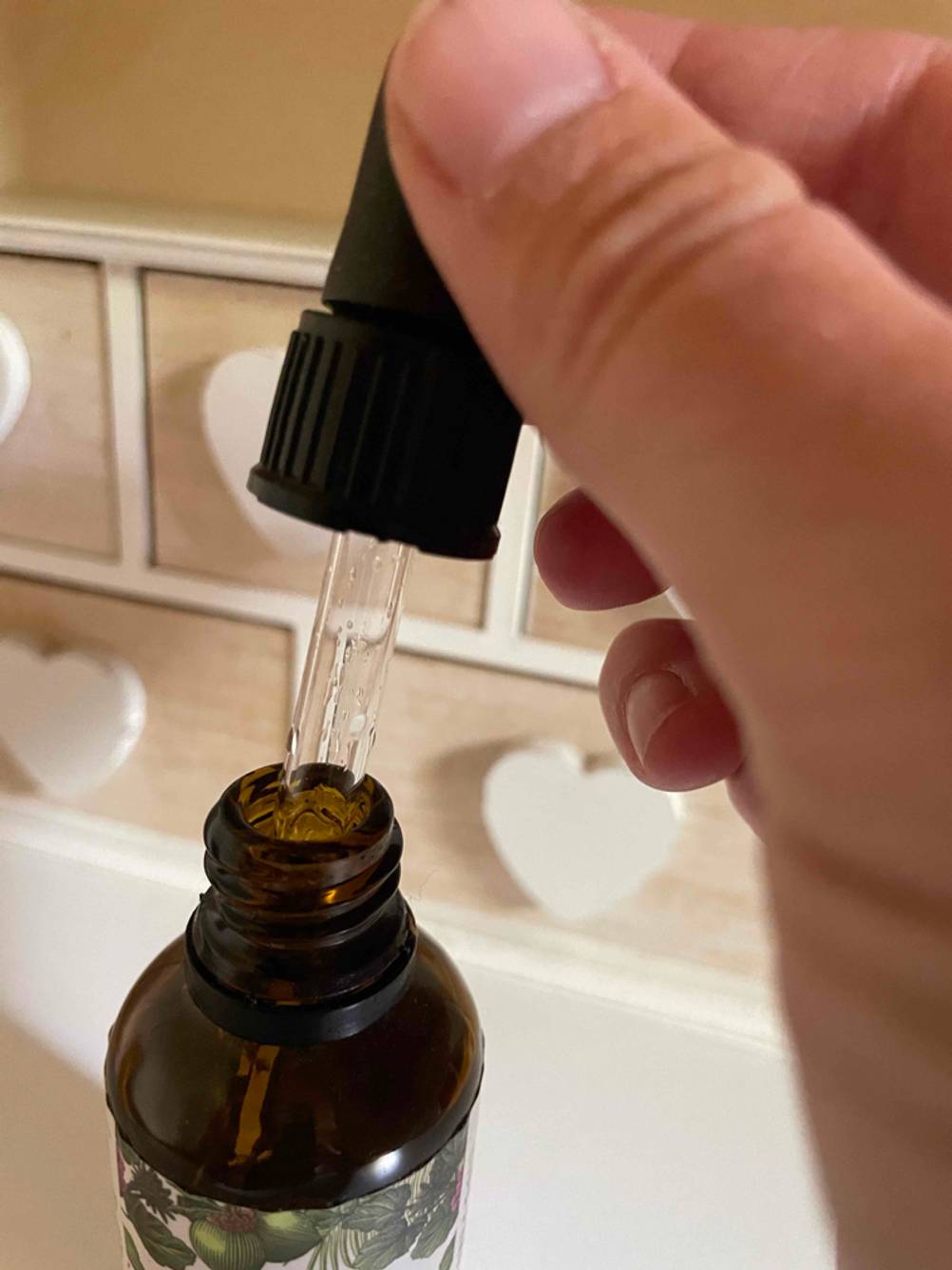 Nahaufnahme der Flaschenöffnung des getesteten Vitamin-D3-K2 aus der eine Hand eine Pipette zieht.