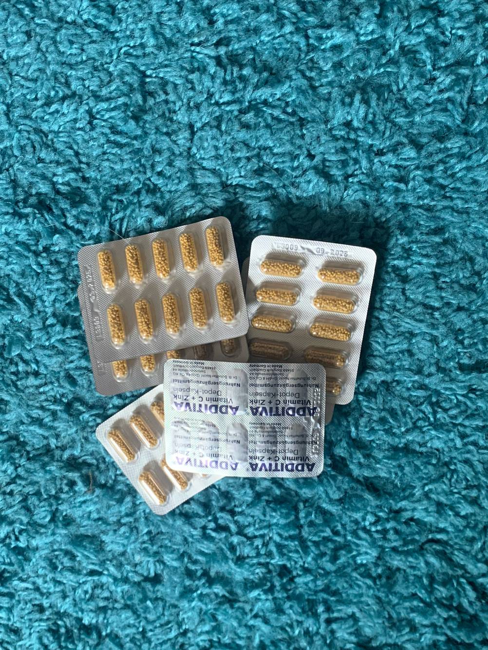 Mehrere Tablettenblister der getesteten Vitamin-Kapseln auf einem blauen Handtuch.