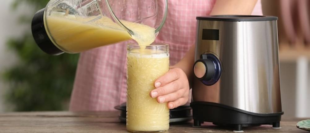 Vitamix-Mixer im Test: Eine Frau füllt einen hellen Smoothie aus einem Mixerglas in ein Trinkglas.