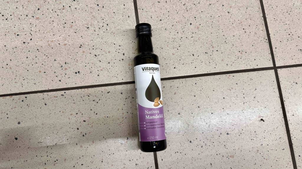Eine 250-ml-Flasche mit Bio-Mandelöl im Test liegt auf dem Boden.