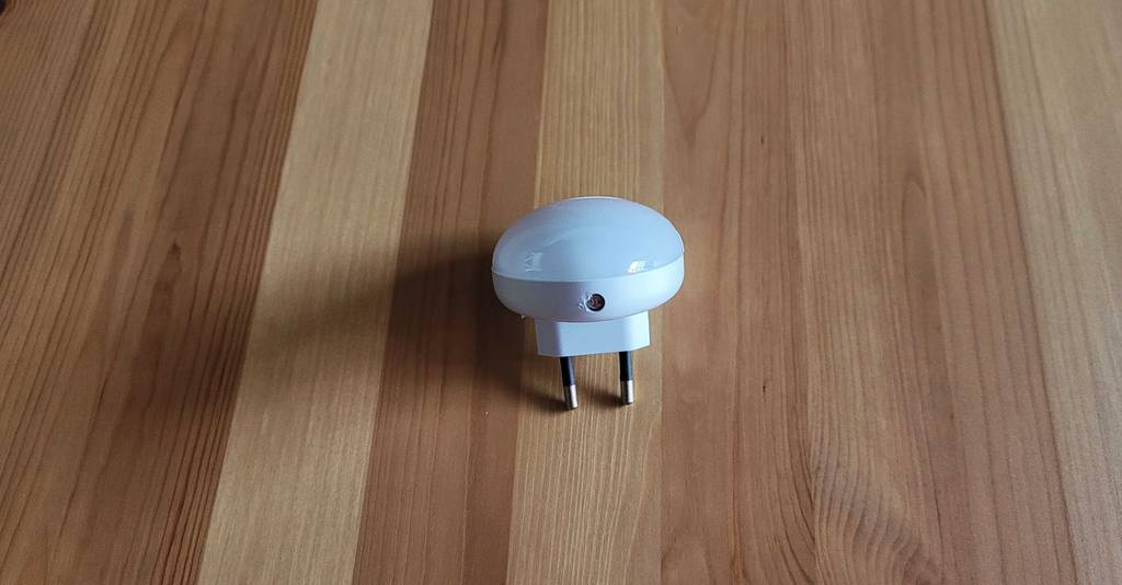 Ein Nachtlicht im Test liegt mit Fokus auf den Euro-Stecker auf einer Holzoberfläche.