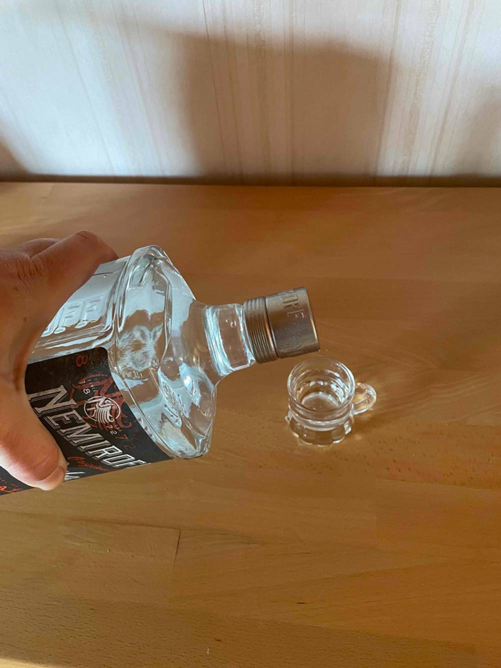 Eine Hand kippt Vodka in ein Glas