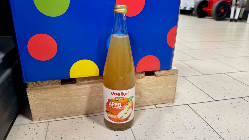 Getesteter Apfelsaft von Demeter in der Glasflasche steht vor einer Palette auf dem Boden.