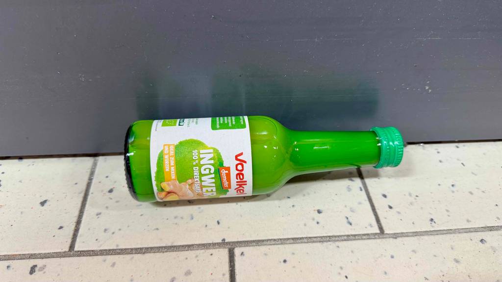 Ingwersaft im Test: Eine transparente Glasflasche mit 100 % Direktsaft liegt auf dem Boden.