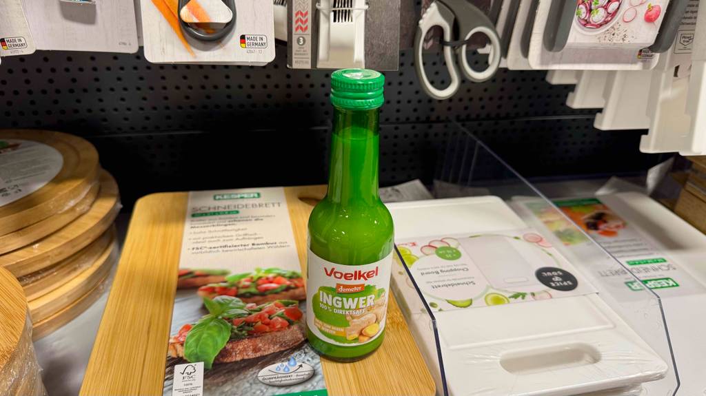 Eine Glasflasche mit getestetem Ingwersaft steht auf einem Regal mit Küchenutensilien.