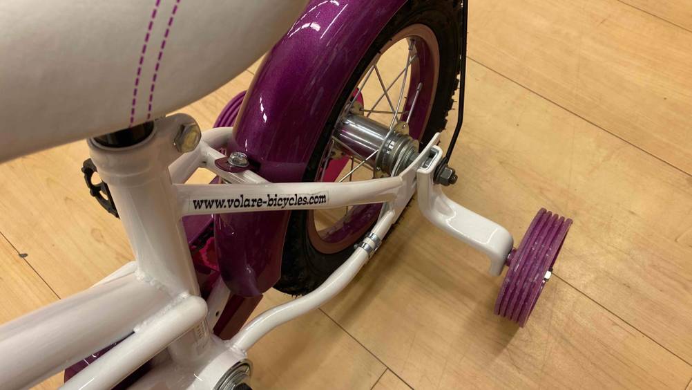 Kinderfahrrad 12 Zoll im Test: An einem Fahrrad sind hinten Stützräder angebracht.