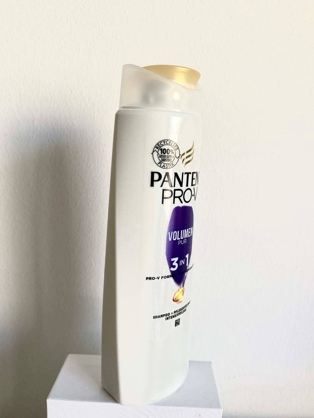 Seitenansicht einer Flasche des getesteten Volumen-Shampoos vor einer hellen Wand.