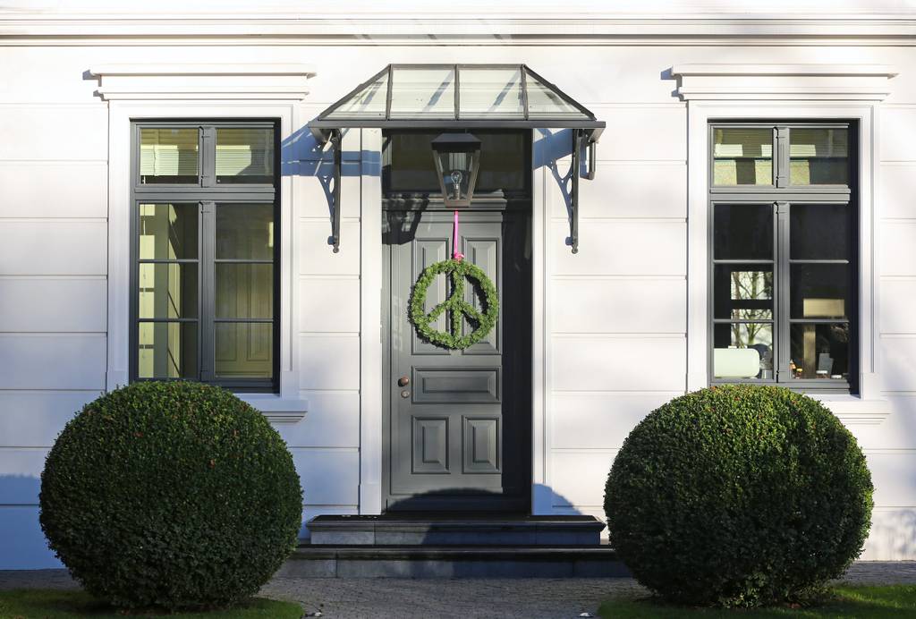 Vordach im Test: Ein Glas-Metall-Vordach an einem älteren Haus – passend im Stil zu Fassade, Fenstern und Tür.