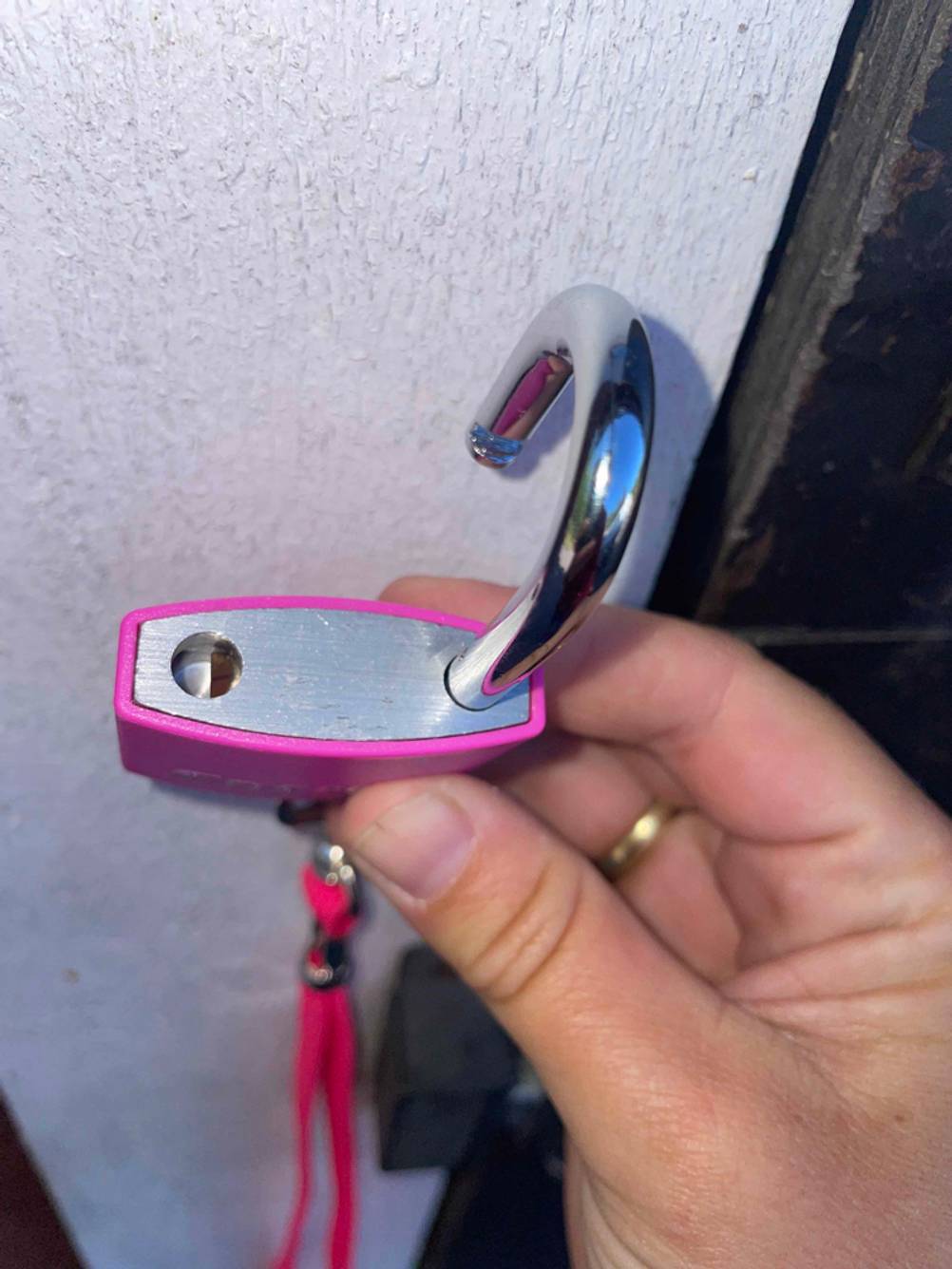 Nahaufnahme eines geöffneten Vorhängeschlosses im Test von oben von einer Hand gehalten.