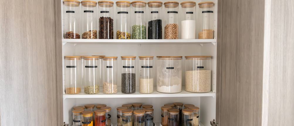 Verschiedene Vorratsgläser im geöffneten Küchenschrank.