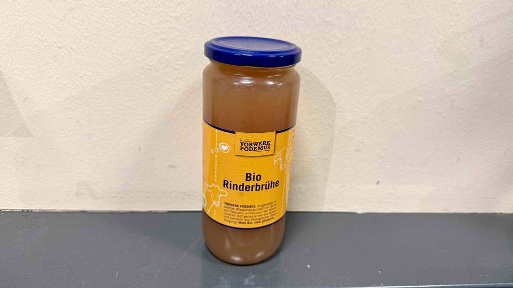Im Test: Rinderbrühe im Glas steht vor einer weißen Wand.