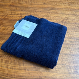 Ein Vossen-Vienna-Style-Supersoft-Handtuch liegt mit einer Papplasche auf einem Tisch