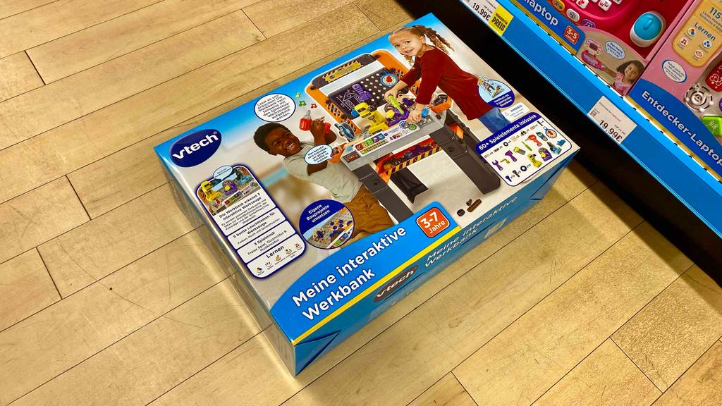 Kinder Werkbank getestet: Originalverpackung liegt quer vor einem Regal auf einem Laminat.