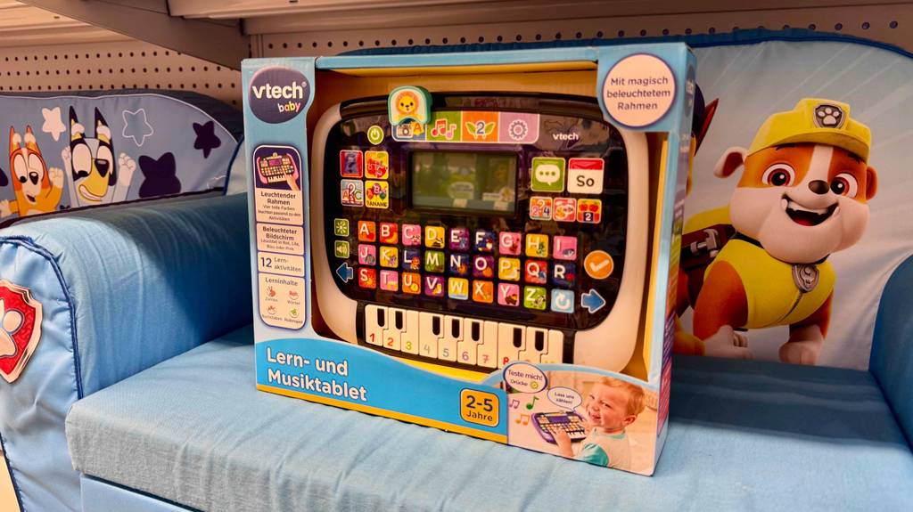 Getestet: Das Lernspielzeug ab 2 Jahren in der Verpackung mit Sichtfenster steht auf einem Kindersofa in Hellblau.