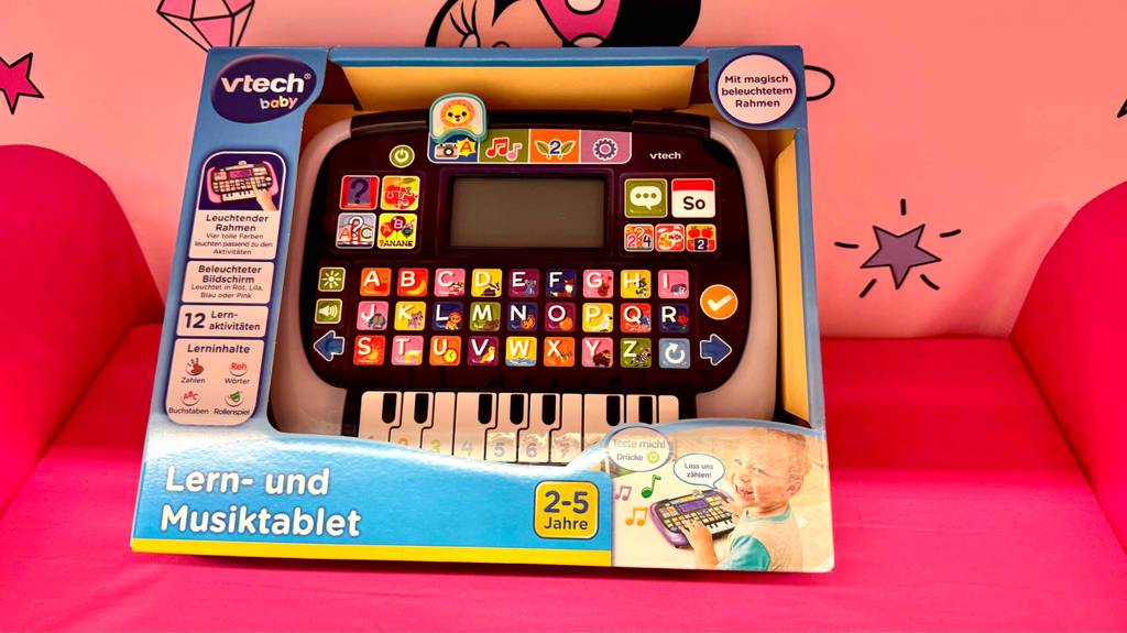 Getestet: Das Lernspielzeug ab 2 Jahren in der Verpackung mit Sichtfenster steht auf einem roten Sessel.