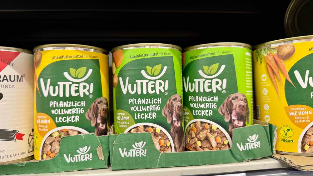 Mehrer Dosen des getesteten veganen Hundefutters stehen in einem Regal.