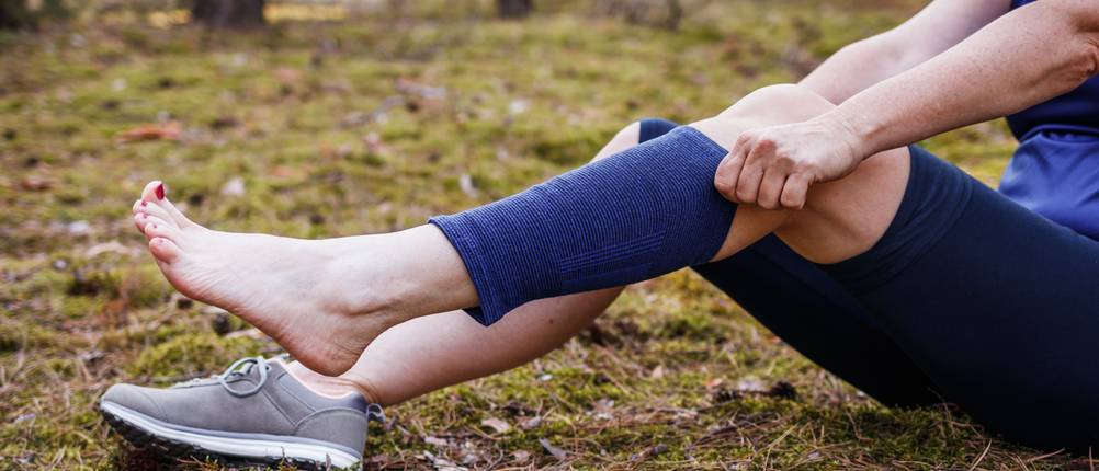 Wadenbandage-Test: Frau zieht Bandage über Wade im Freien.
