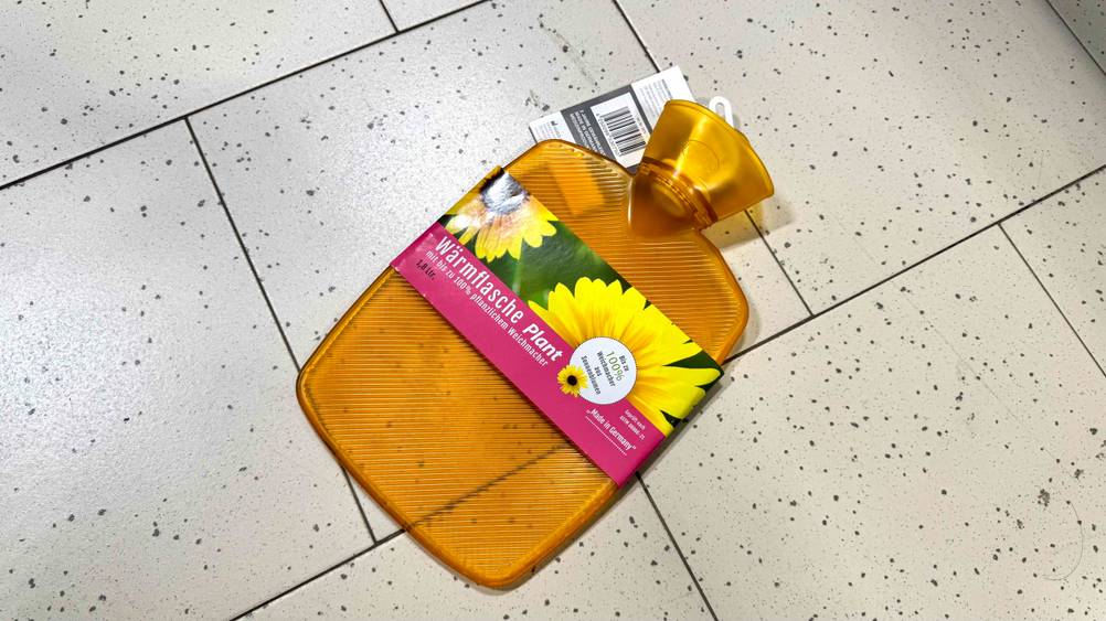 Wärmflasche-Gummi im Test: Eine Flache liegt quer auf einem hellen Boden.