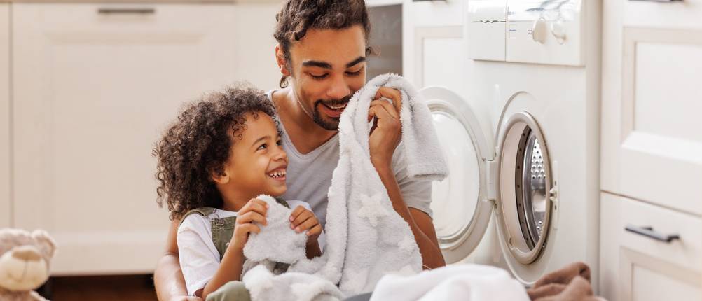 Waschmaschine getestet: Vater und Sohn waschen Wäsche.