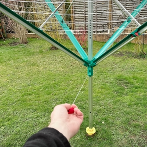 Die Leifheit Linomatic 600 Deluxe ist halb aufgeklappt. Eine Hand zieht am roten Griff.