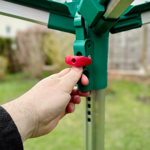 Eine Hand greift zur Höhenverstellung der Leifheit Linomatic 600 Deluxe am Hauptgestänge.
