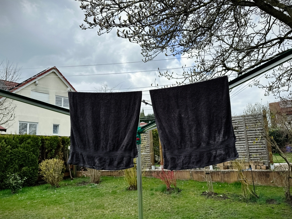 Zwei schwarze Handtücher hängen an der Leifheit Linomatic 600 Deluxe im Garten.