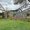 Die Leifheit Linomatic 600 Deluxe steht geöffnet im Garten mit aufgespannten Leinenarmen.