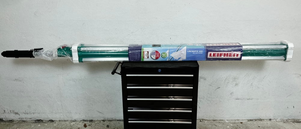 Die verpackte Leifheit Linomatic 600 Deluxe liegt quer auf einem Rollcontainer im Innenraum.