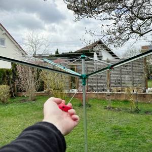Die Leifheit Linomatic 600 Deluxe steht vollständig geöffnet im Garten auf dem Rasen.