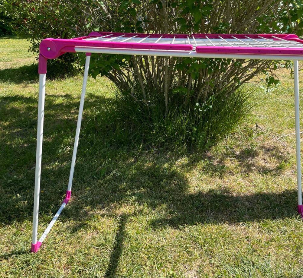 Seitenansicht eines getesteten Wäscheständers vor einem Busch.