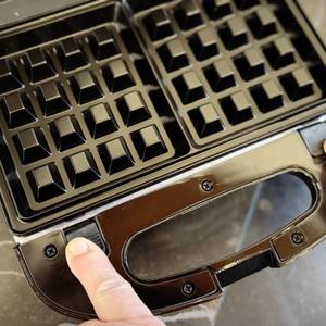 Eine Person entriegelt die Wechselplatte beim getesteten Waffeleisen von Russell Hobbs.
