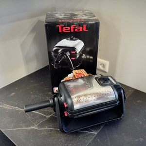 Das getestete Waffeleisen von Tefal steht zusammen mit der Verpackung auf einer dunklen Arbeitsfläche.