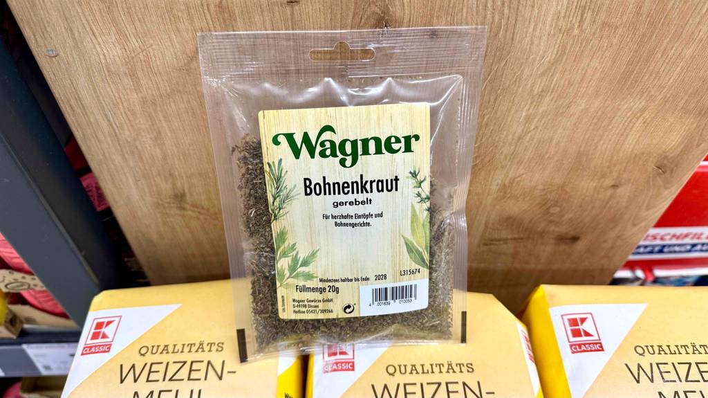 Eine Packung Bohnenkraut steht zum Testen auf Mehlpackungen vor einer Holzwand.