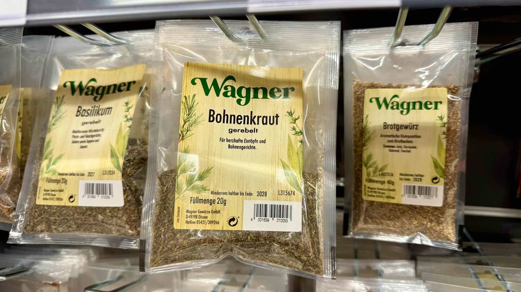 Bohnenkraut im Test: Mehrere Packungen hängen zwischen anderen Gewürzen in einem Regal.