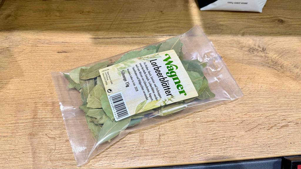 Eine Packung Lorbeerblätter liegt zum Testen auf einem Holzbrett.