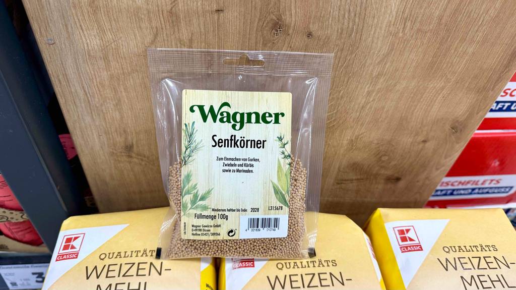 Senfkörner im Test: Eine Packung steht auf mehreren Mehlpackungen vor einer Holzwand.