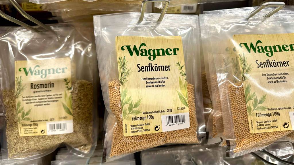 Senfkörner im Test: Mehrere Packungen hängen neben anderen Gewürzen in einem Regal.