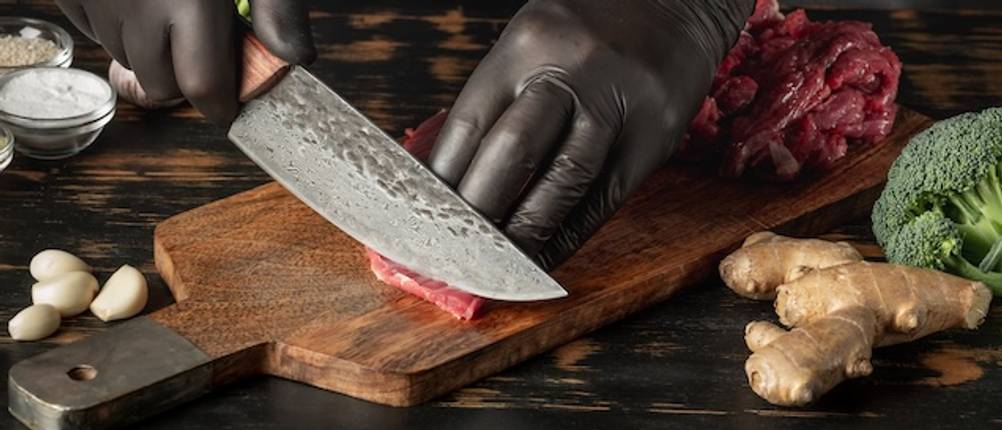 Wakoli-Damastmesser-Set beim Fleisch schneiden auf einem Holzbrett getestet.