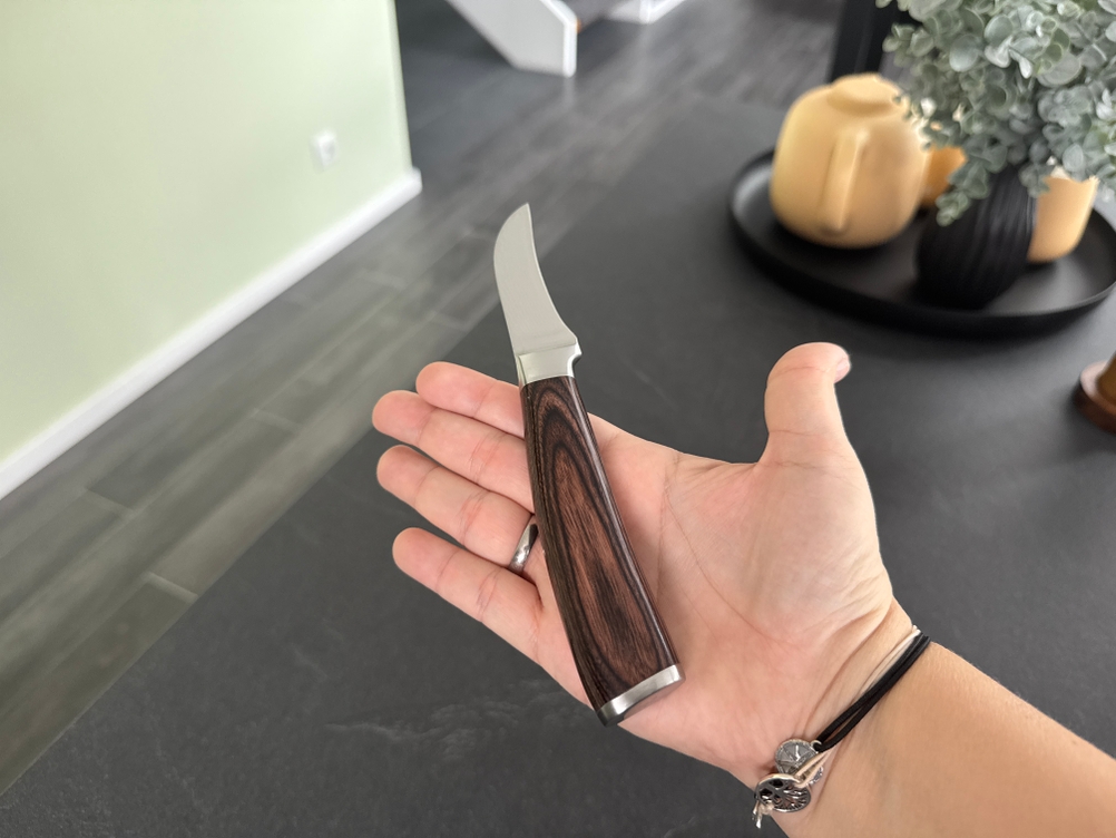 Das Wakoli-Edib-Schälmesser liegt in einer geöffneten Hand.