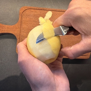 Mit einer Hand wird die Nashi-Birne mit dem Wakoli-Schälmesser geschält.
