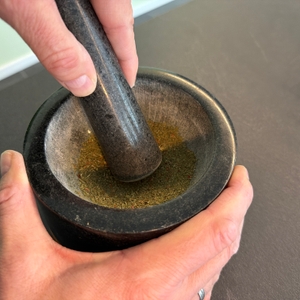 Kräuter werden im Waldwerk-Mörser zerkleinert.